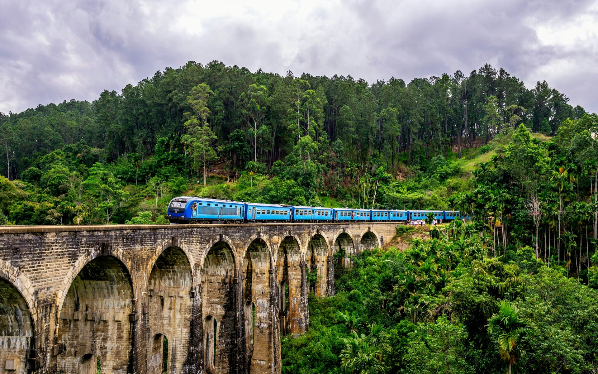 Nine Arch Bridge Ella with blue train crossing — wide landscape view