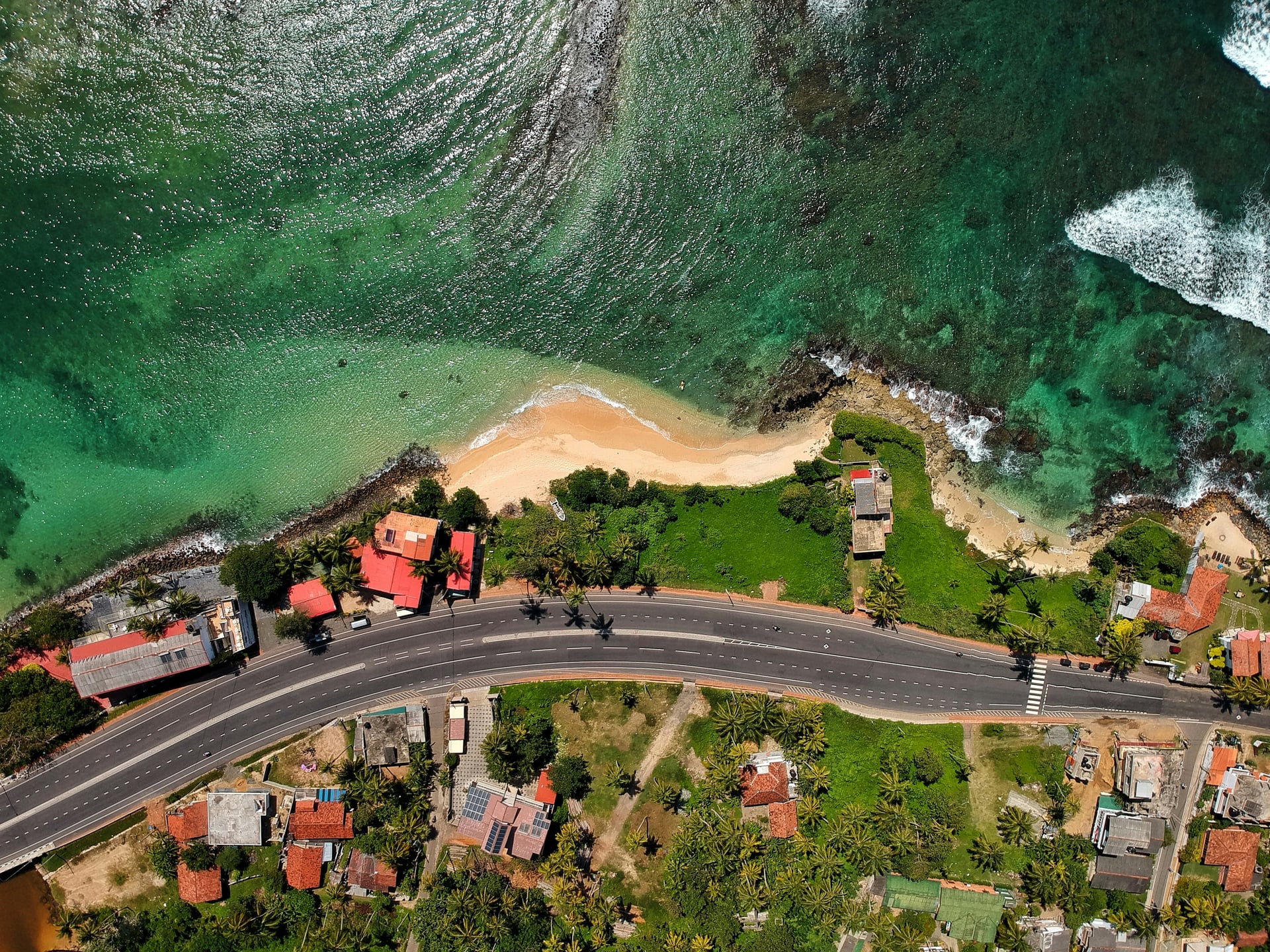 Aerial view of coastal road curving past a sandy beach cove