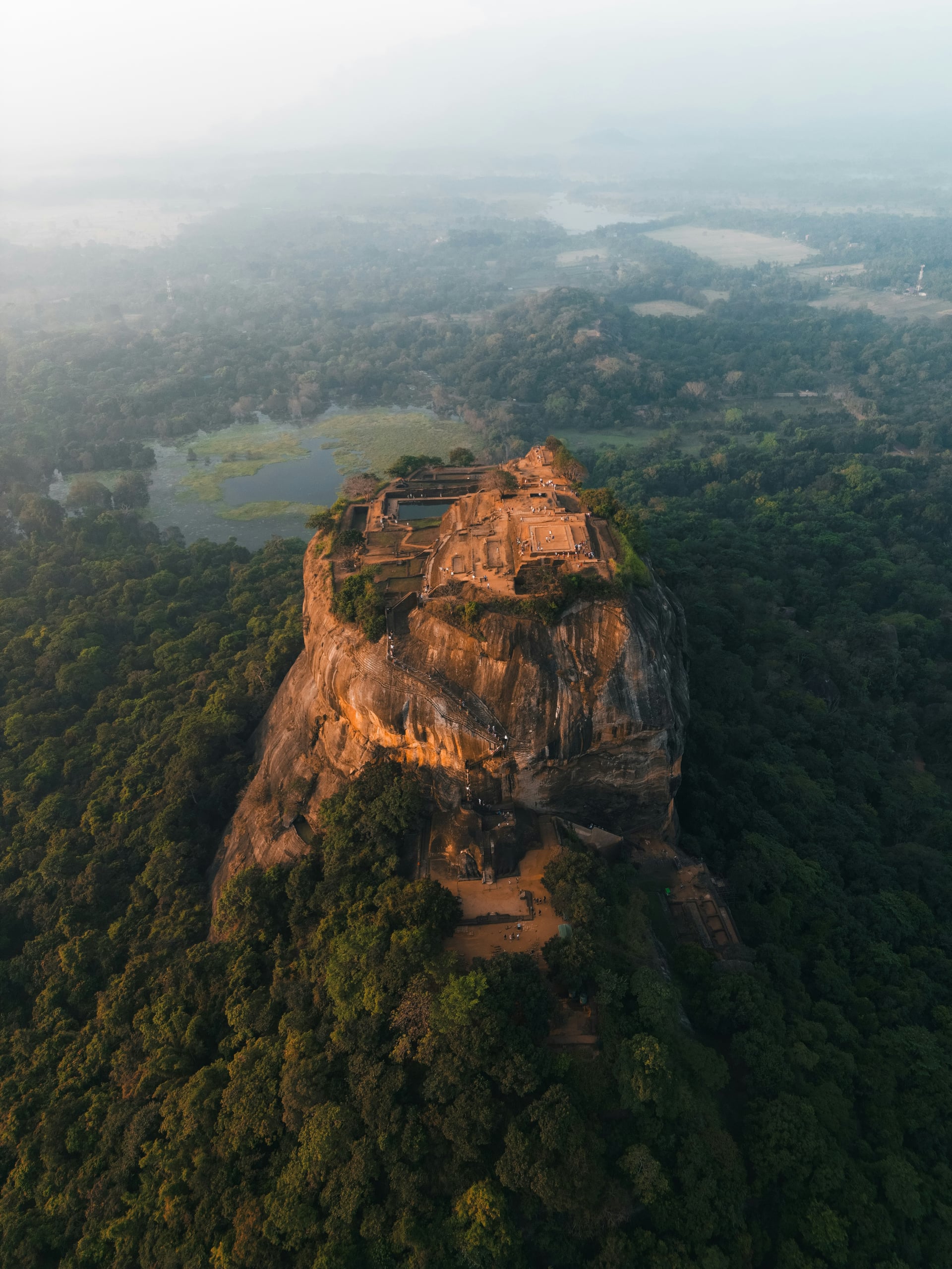 Aerial view of Sigiriya Rock Fortress rising dramatically from jungle mist