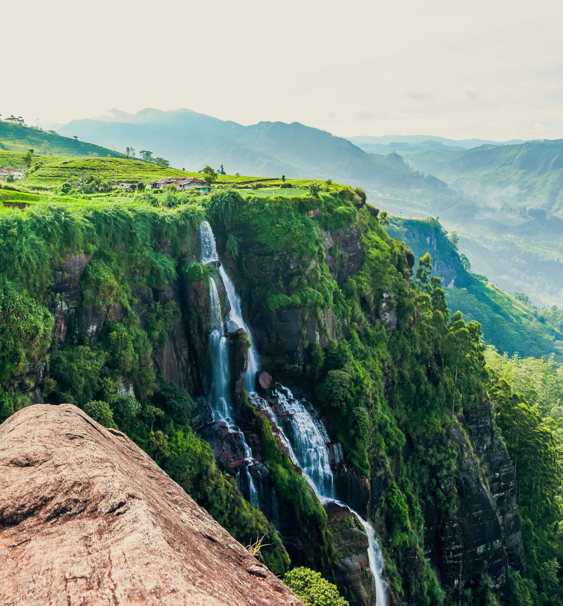 Waterfall cascading off a tea estate cliff edge in Sri Lanka hill country