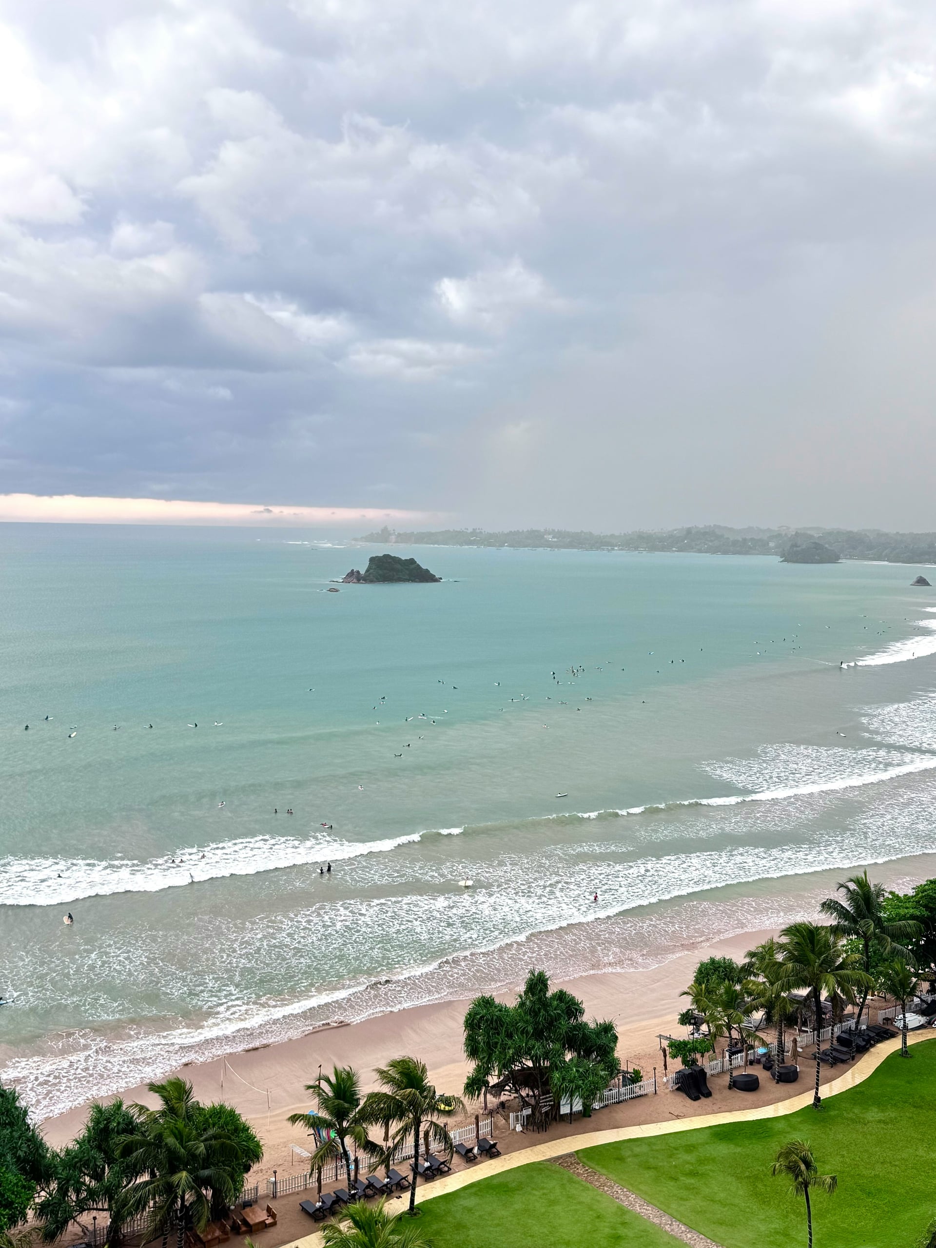 Trincomalee Nilaveli beach with surfers and a small offshore island in the distance