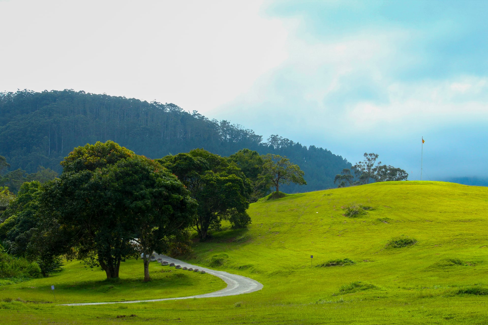 Nuwara Eliya golf course with lush rolling hills and misty forest backdrop