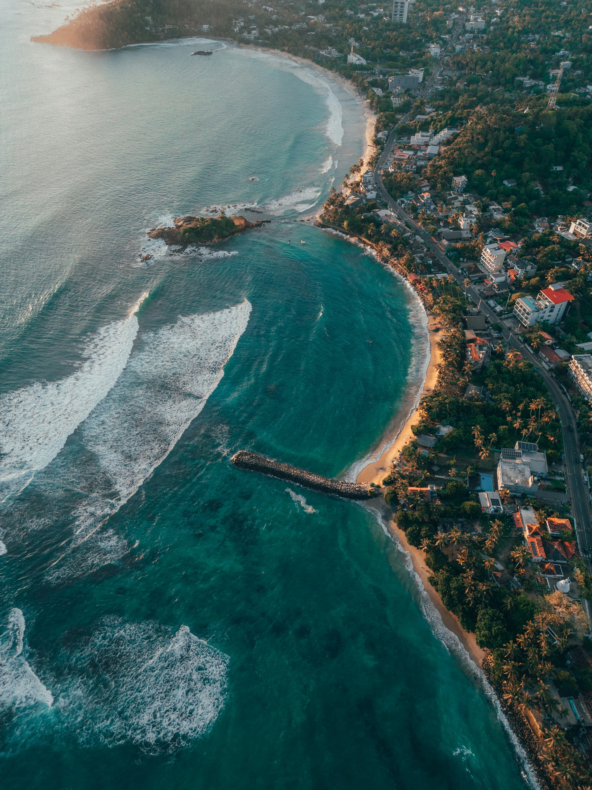 Aerial view of Mirissa bay at golden hour with coastal town below
