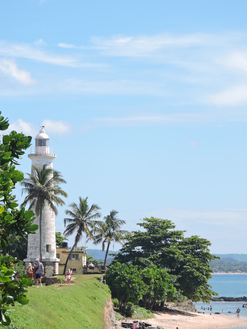 Galle Fort lighthouse with palm trees and sandy beach on a sunny day