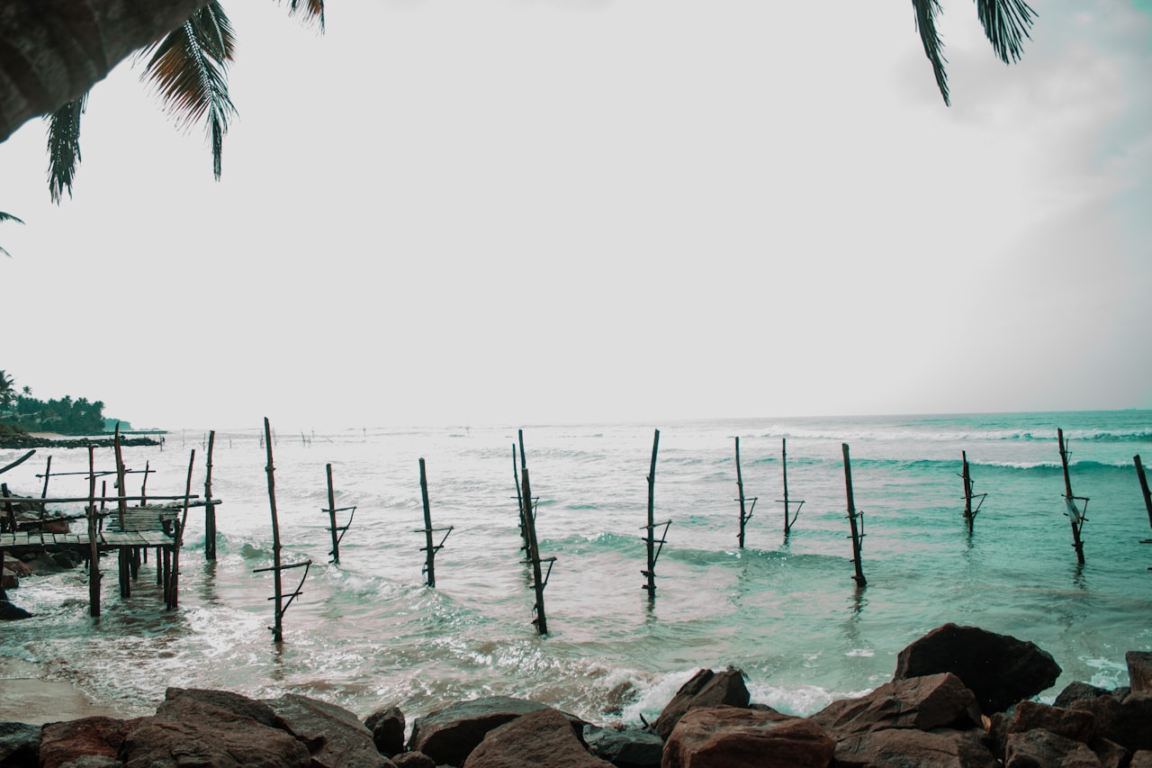 Traditional stilt fishermen perched on poles in the ocean near Hikkaduwa